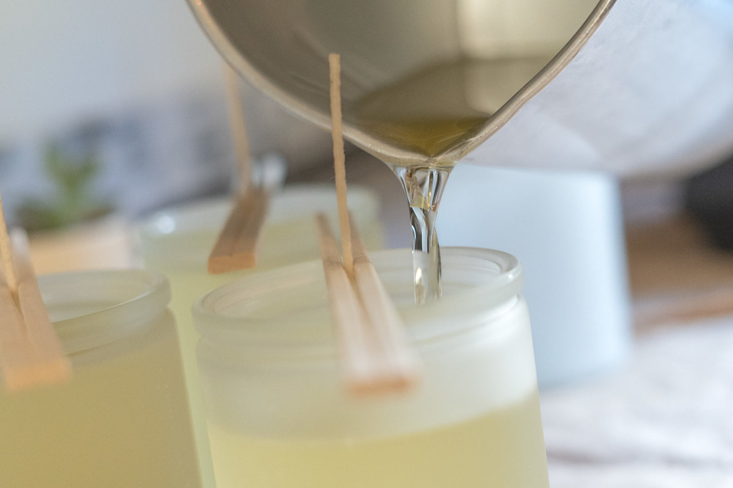 Image of wax being poured into a frosted glass vessel